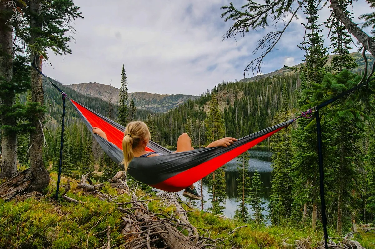 A person relaxing in a hammock above a mountain lake