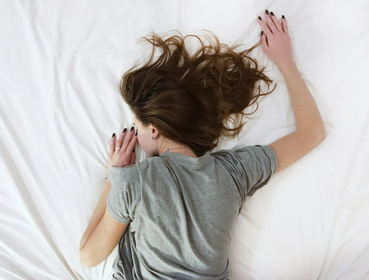 A person sleeping soundly in bed, stretched out under soft covers