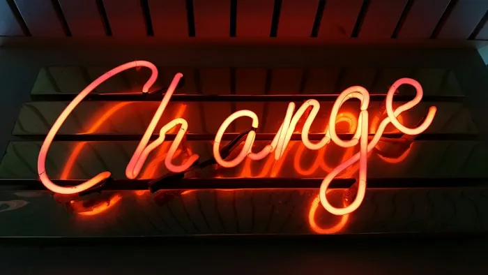 A neon sign in red and orange script reading Change on a dark wall
