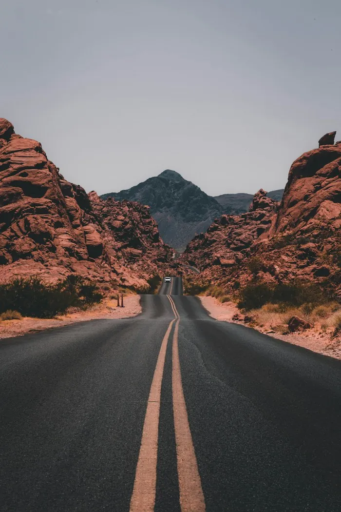 A long road winding through red rock desert toward mountains