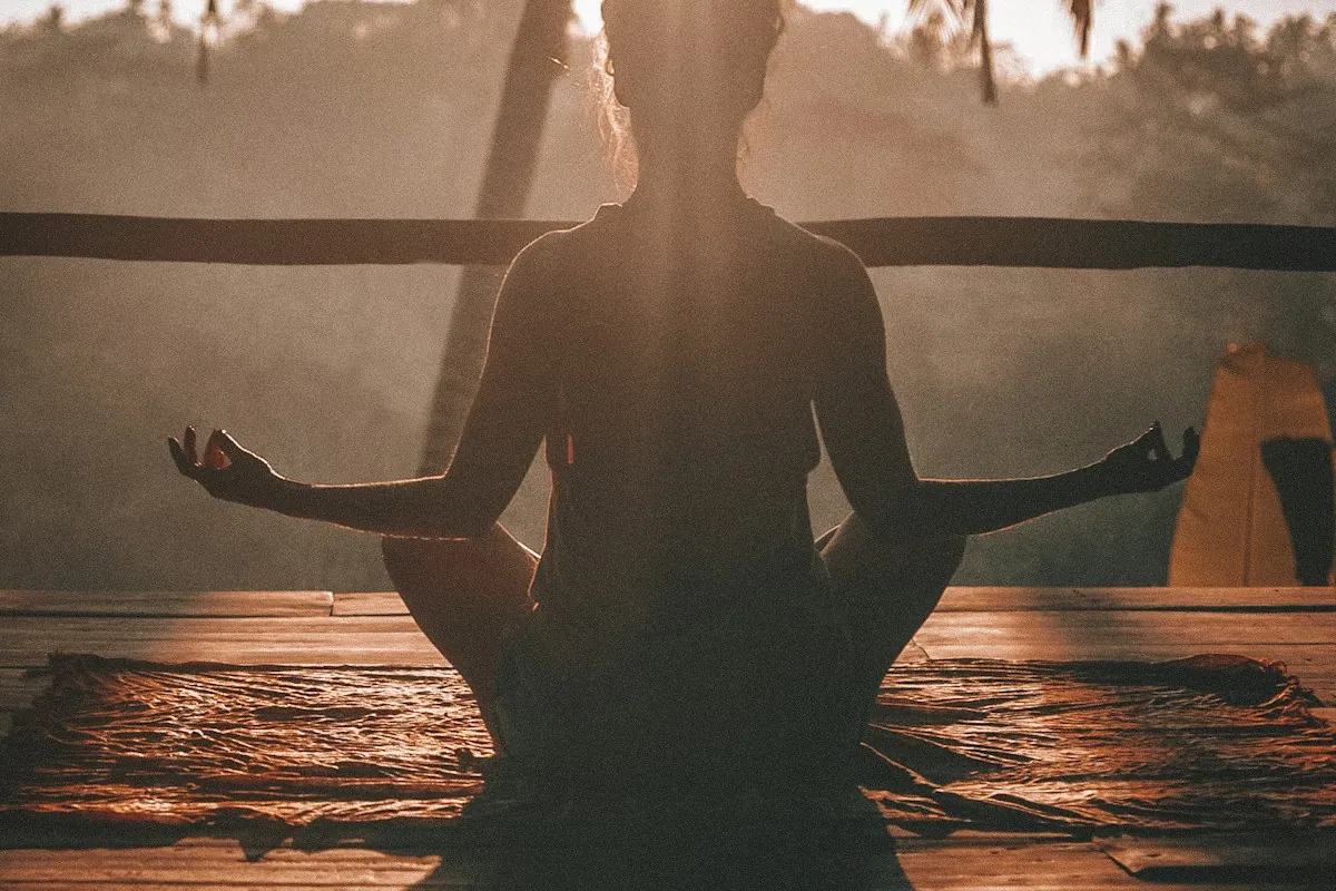 A person sitting cross-legged in meditation in warm evening light