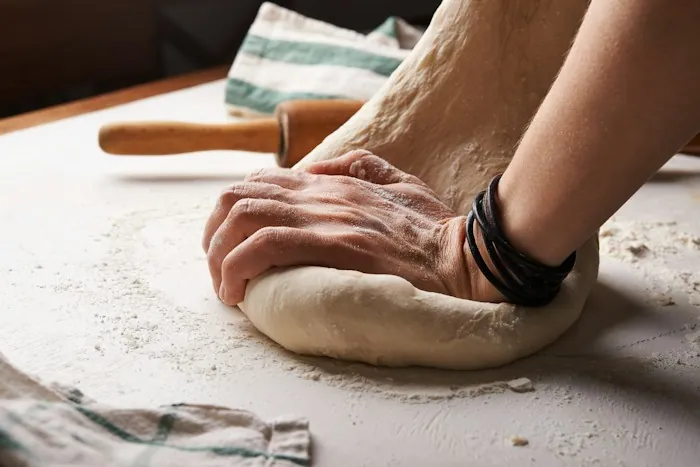 Hands kneading dough on a floured surface