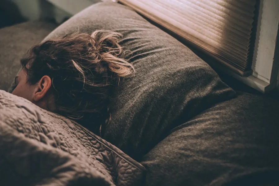 A person resting their head on a soft pillow in warm, dim light
