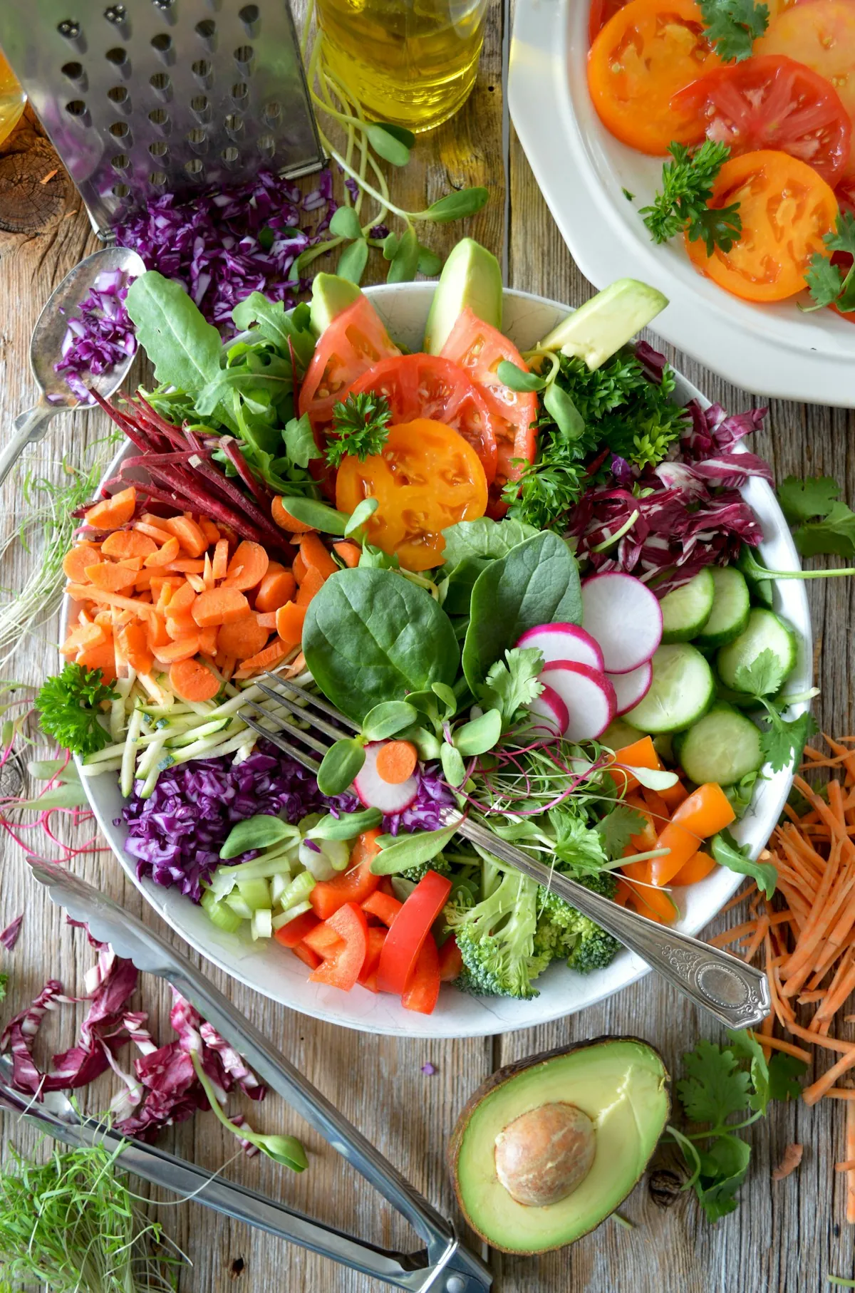 A large bowl of colorful fresh salad with tomatoes, radishes, carrots and leafy greens