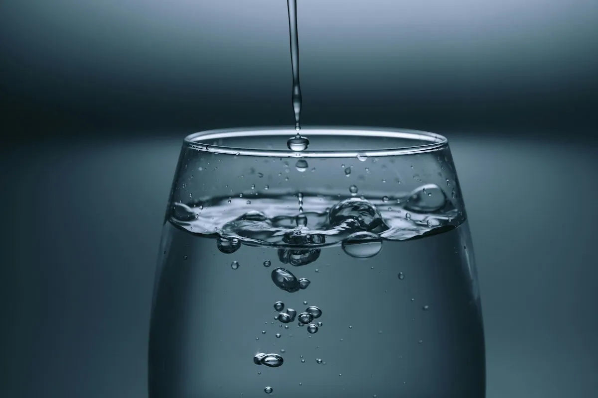 Water pouring into a clear glass against a dark background