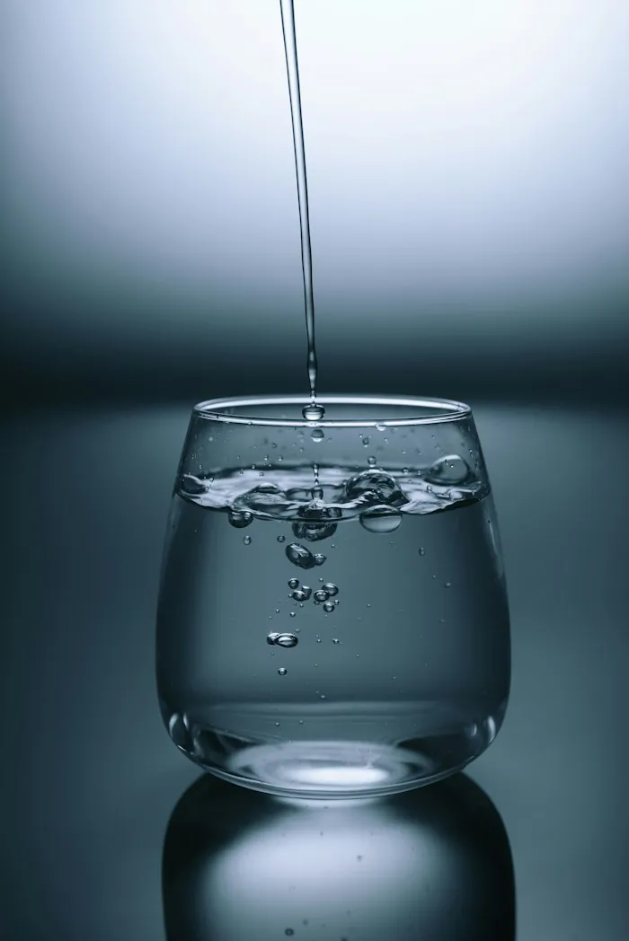 Water being poured into a clear glass against a dark background