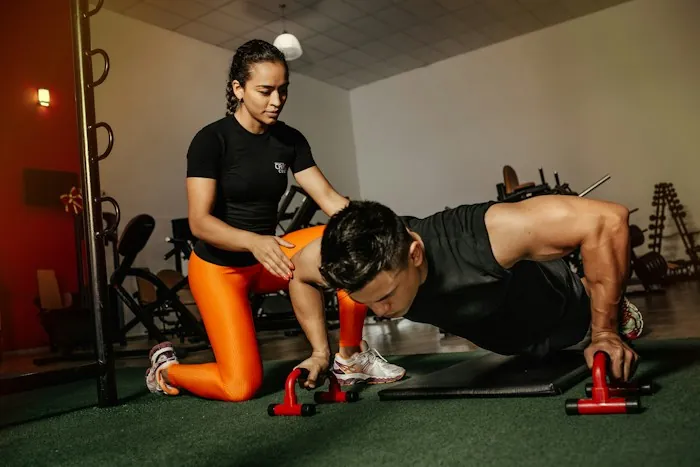 A trainer guiding a client through a push-up in a gym