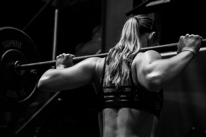 A woman performing a barbell back squat, shown in black and white