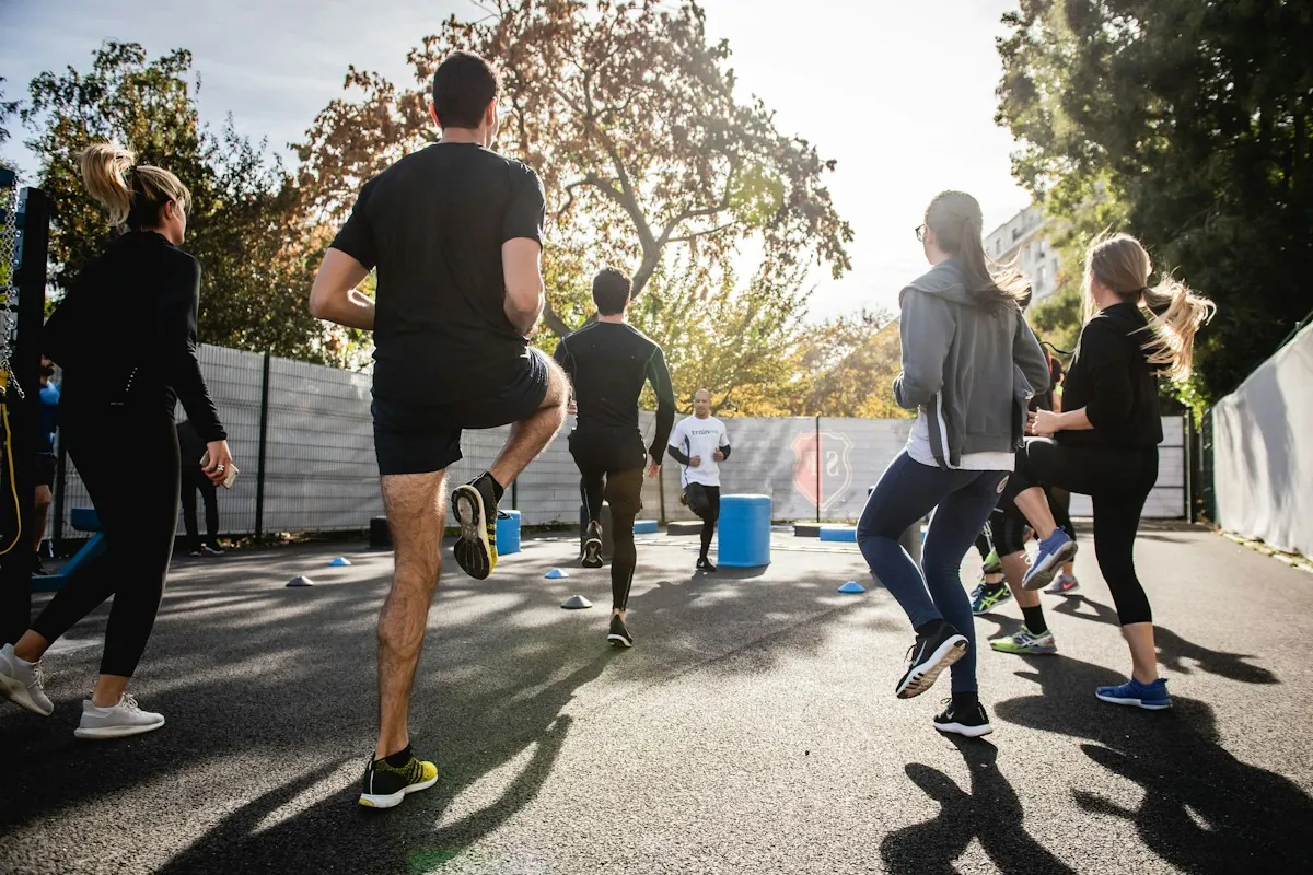 A group of people doing a bodyweight workout together outdoors on a sunny street