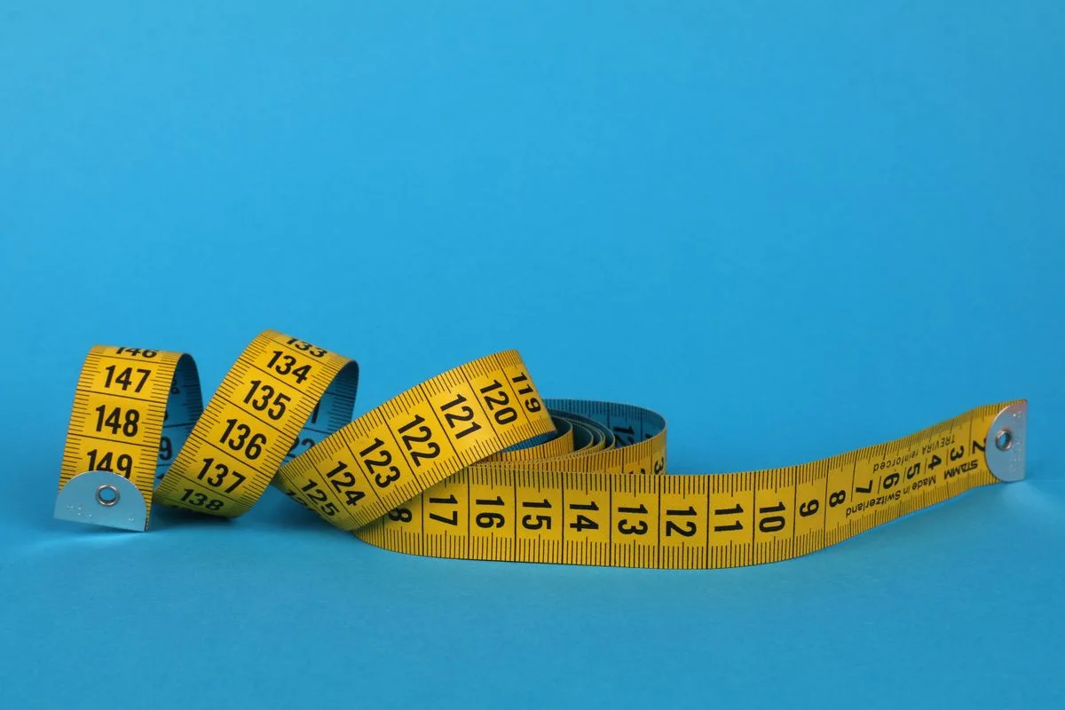A coiled yellow tape measure on a blue background