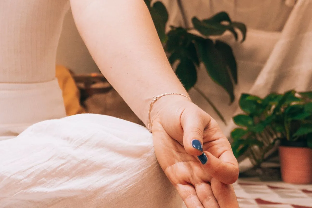 A close view of a relaxed hand resting beside houseplants