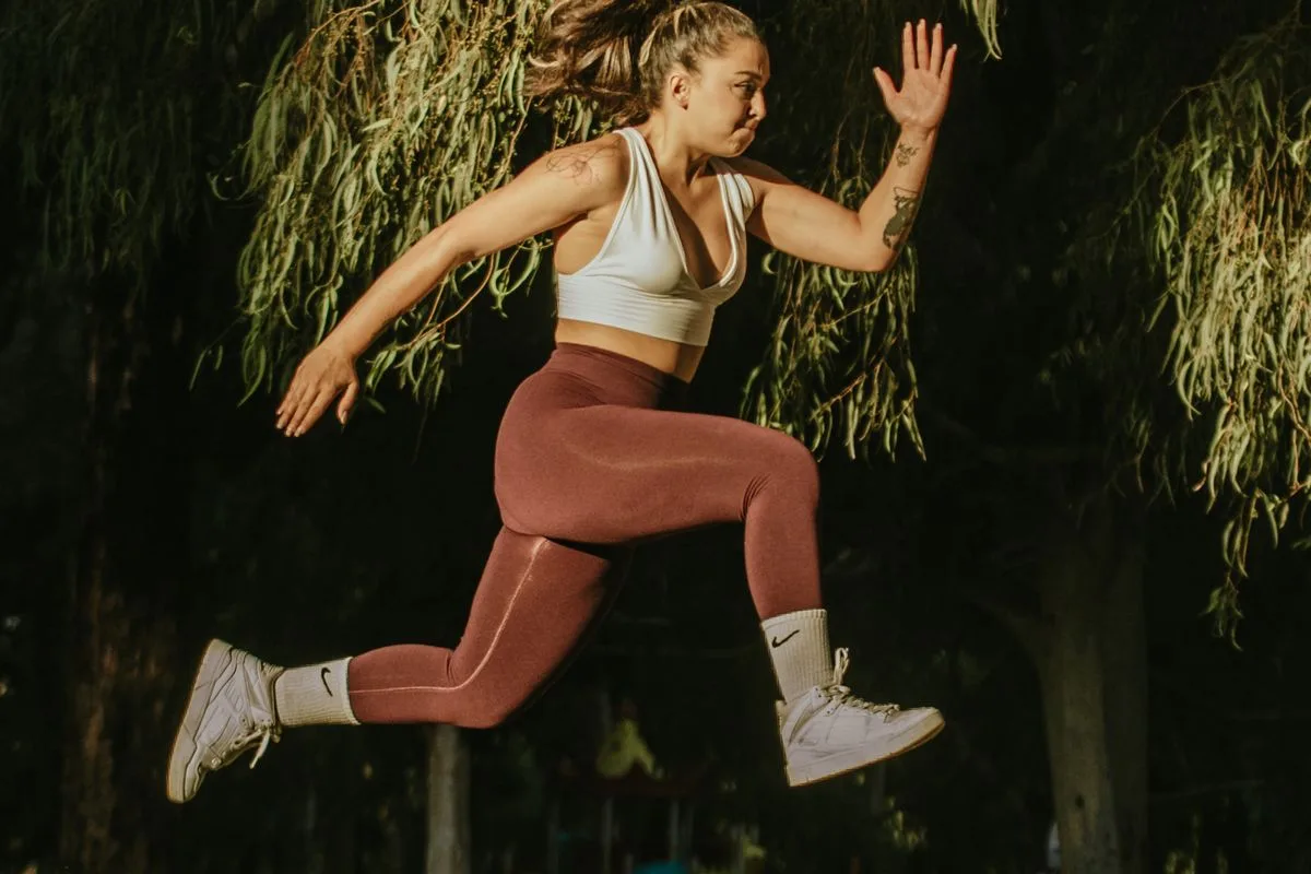A woman leaping mid-stride outdoors in activewear, full of energy