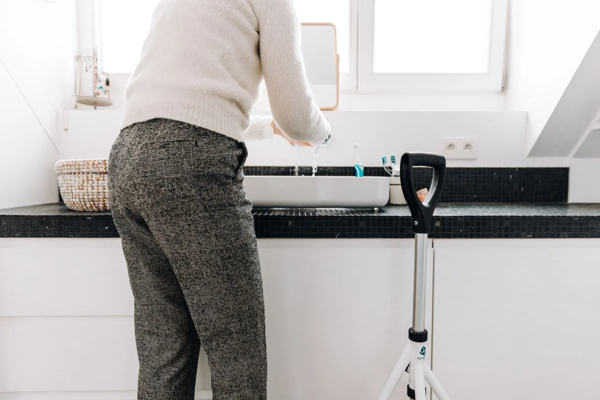 An older woman using a mobility walker in a bright, modern bathroom