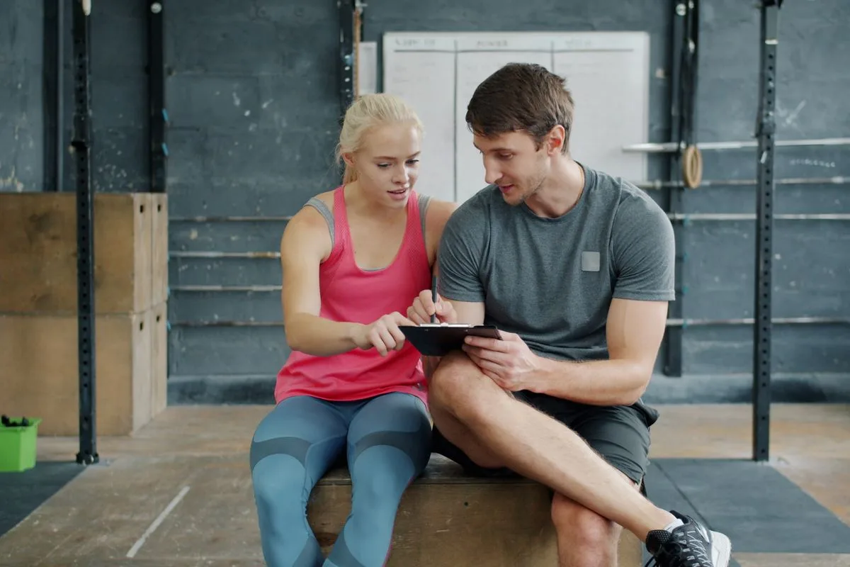A man and woman reviewing a training plan together in a gym