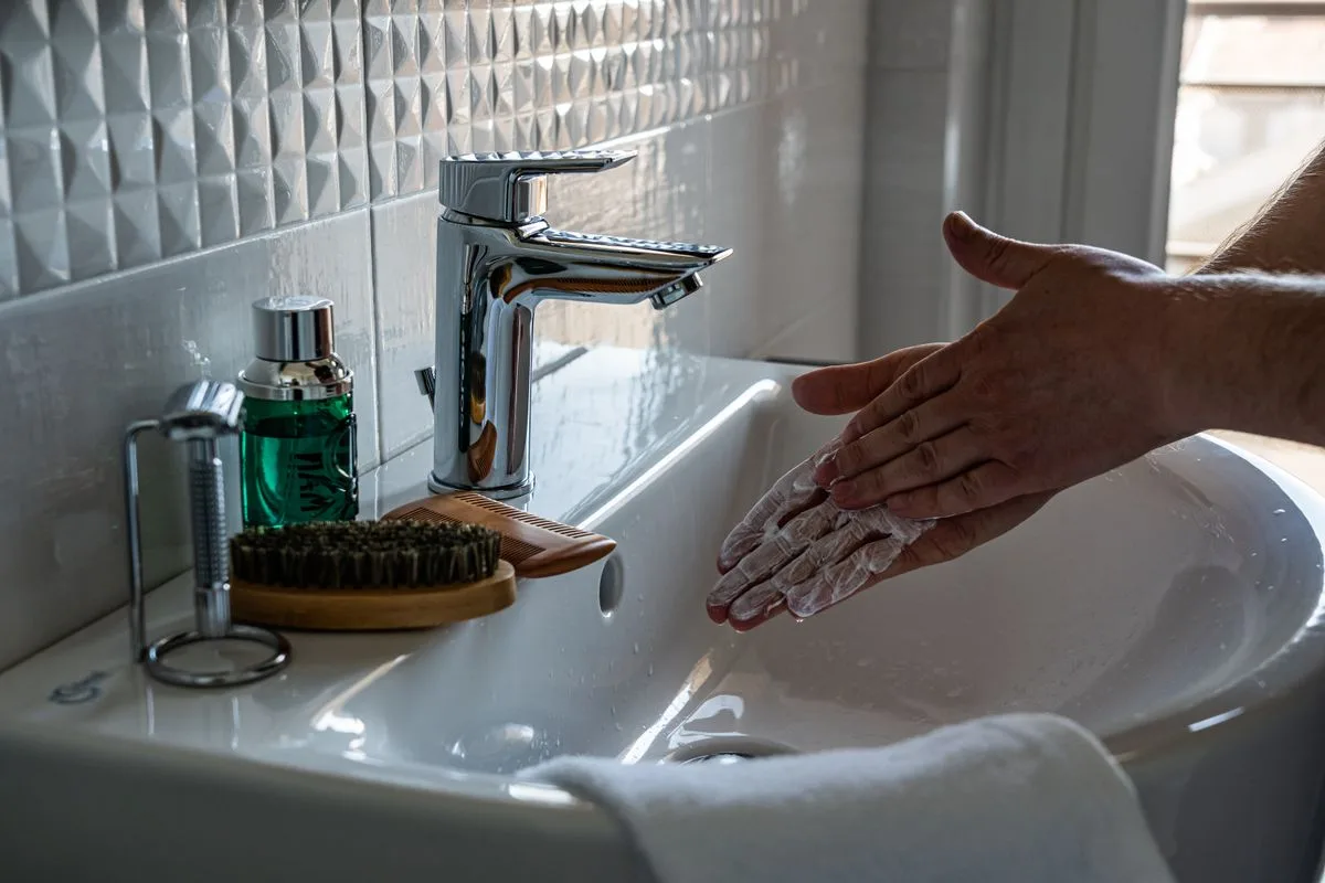 Close-up of hands being washed with soap under running water