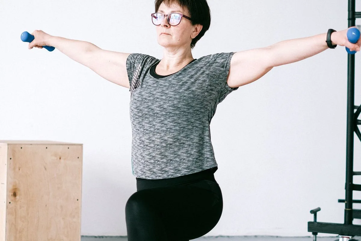 A mature woman lifting light dumbbells with arms outstretched