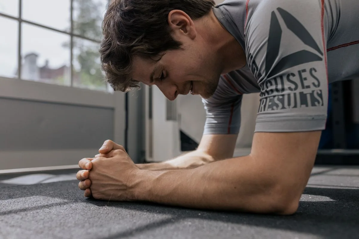 A man holding a plank position with hands clasped on the floor