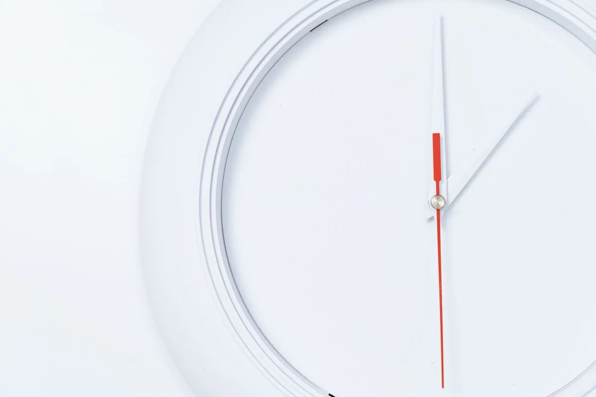 A minimalist white clock face with red and white hands, representing a timed eating window