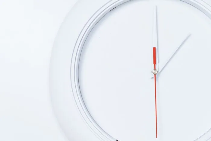 A minimalist white clock face with red and white hands, representing a timed eating window
