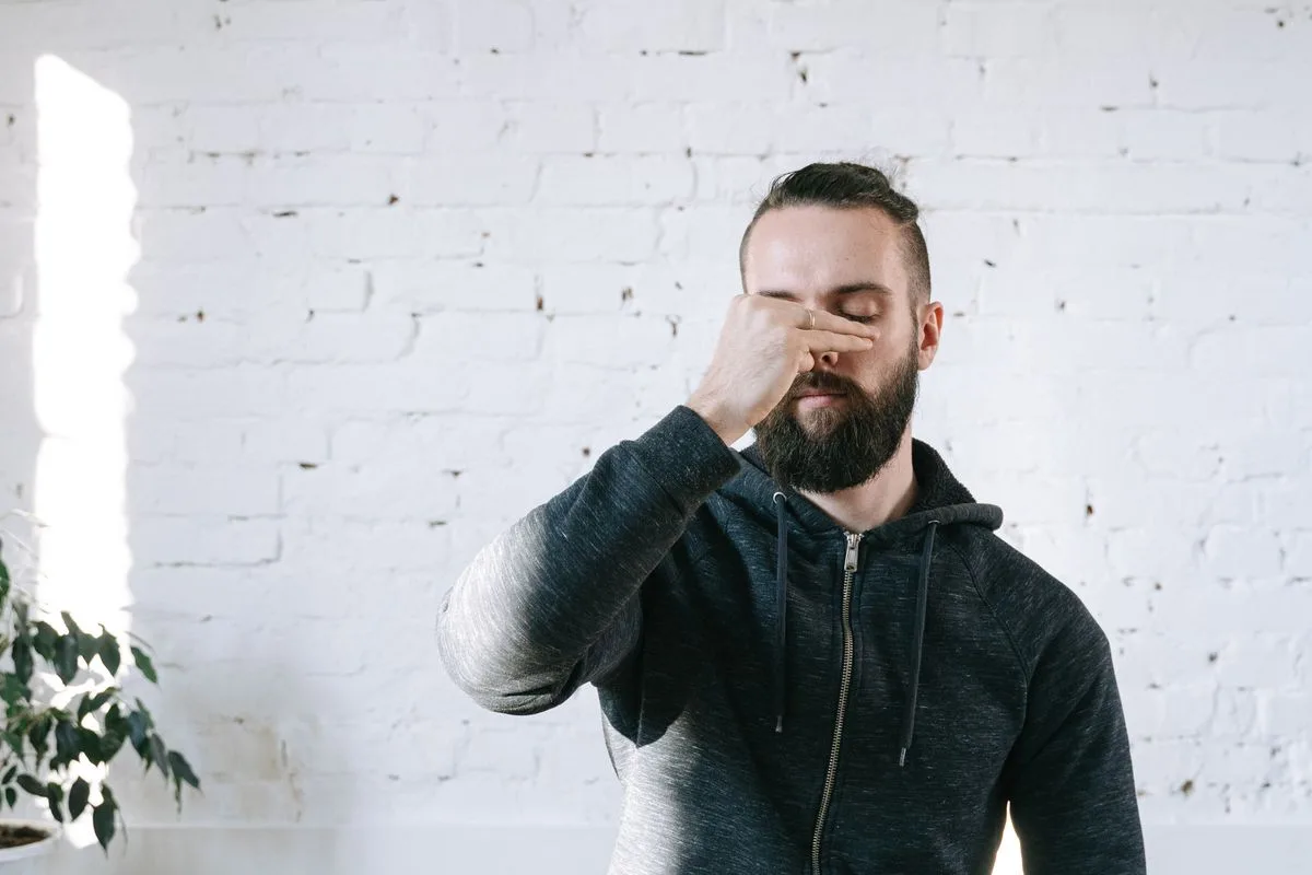 A bearded man practicing a slow breathing exercise indoors