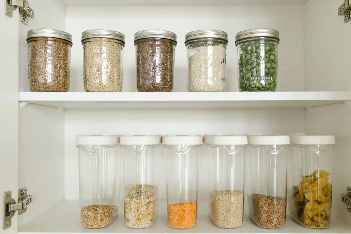 Neatly organized glass jars of grains and pulses on open kitchen shelves