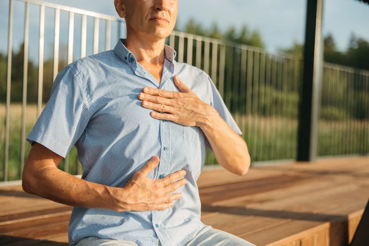 A person resting both hands on their chest, pausing to breathe